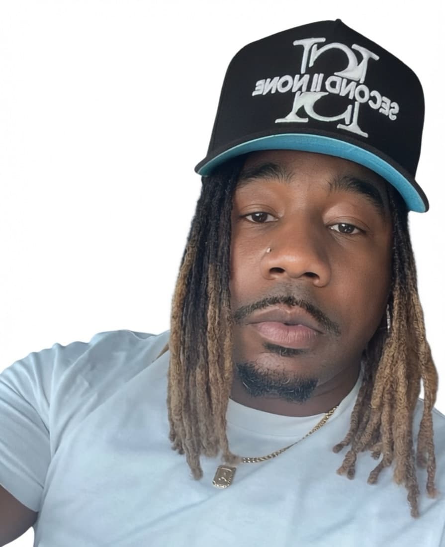 Person with shoulder-length locs wearing a black and blue Second II None cap