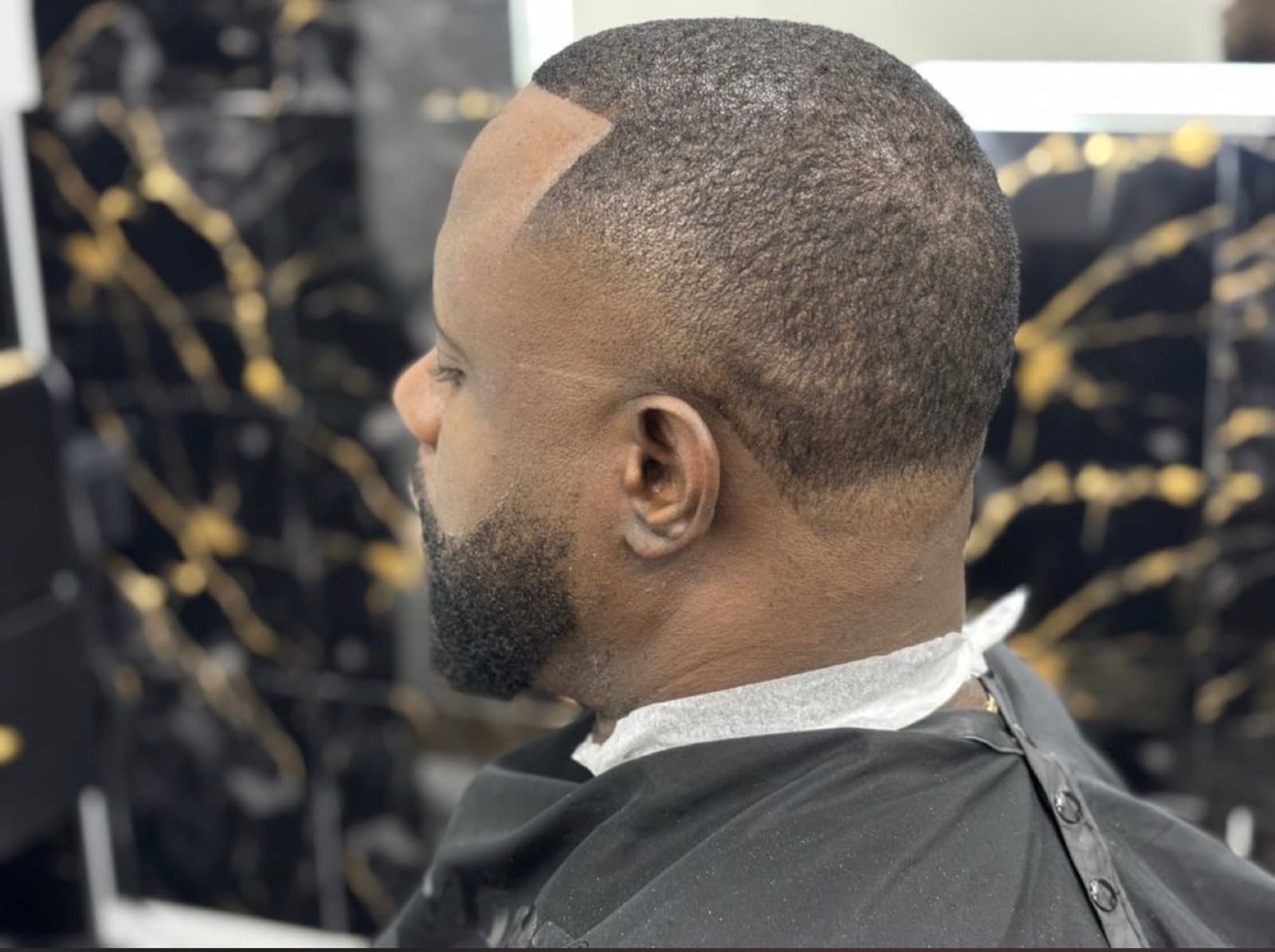Skin fade blended into a sharp beard on a marble backdrop
